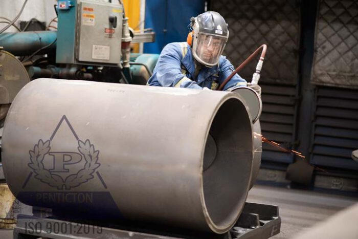 Grinding a piece of pipe that will eventually combine chrome white iron and steel