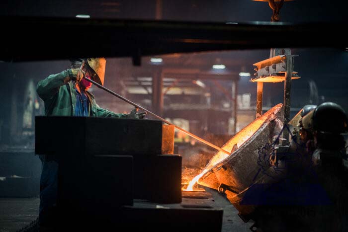 A foundry worker pours ASTM A536 120 – 90 – 02 ductile iron
